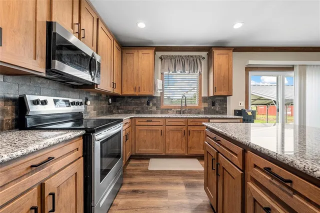 a kitchen with stainless steel appliances granite countertop a stove a sink and a microwave
