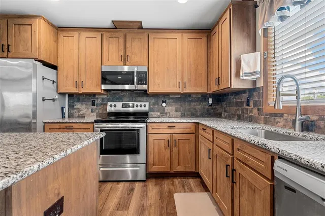 a kitchen with kitchen island granite countertop a sink cabinets and stainless steel appliances