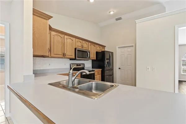 a kitchen with stainless steel appliances a sink a microwave a refrigerator and cabinets