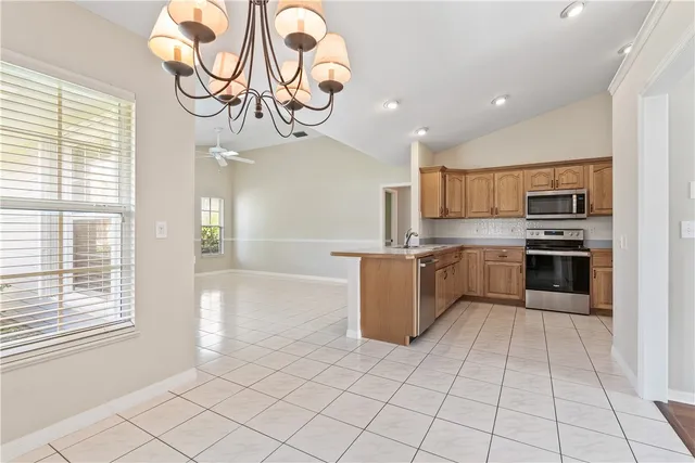 a large kitchen with stainless steel appliances granite countertop a stove top oven a sink dishwasher and a refrigerator with wooden floor