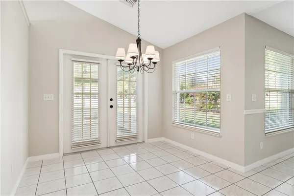 a view of an empty room with window and chandelier fan