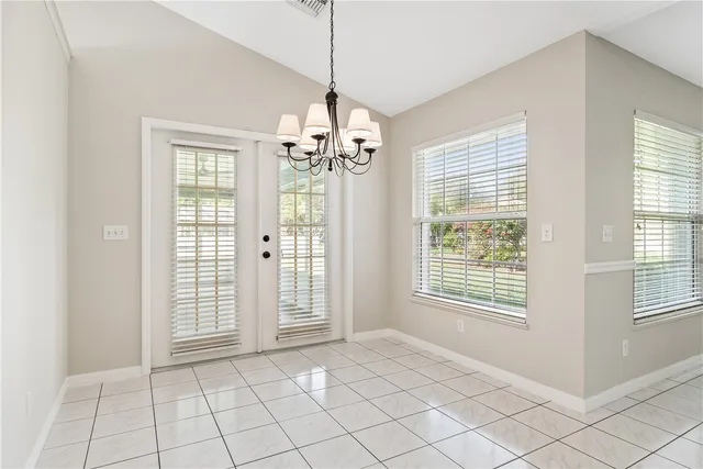 a view of an empty room with window and chandelier fan