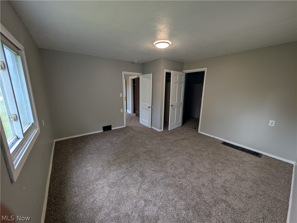 475 East 146th Street Cleveland, OH 44110 - Photo 19 of 28 Neutral-toned room featuring a window, textured carpet flooring, and multiple interior doors