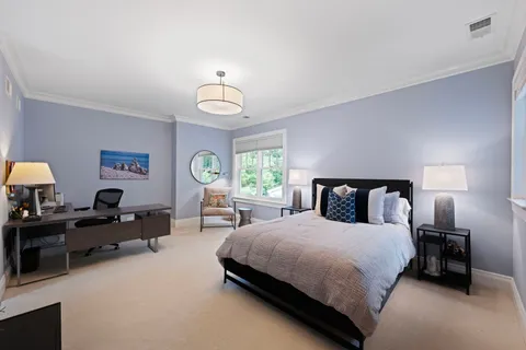 a bedroom with bed a chandelier and a flat tv screen