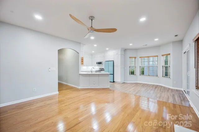 a view of an empty room with wooden floor and a kitchen