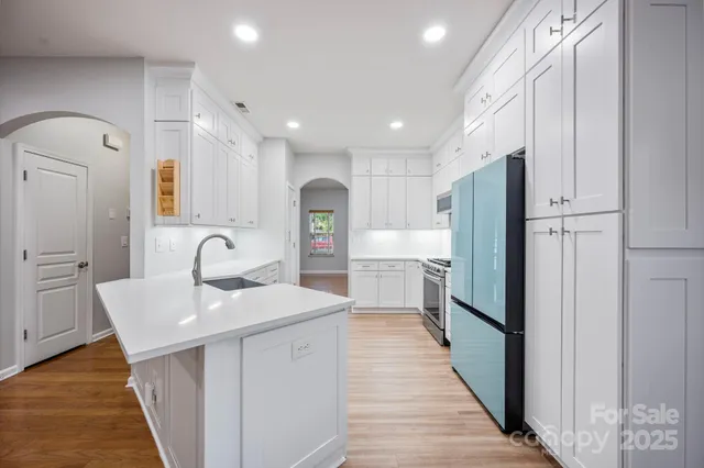a kitchen with stainless steel appliances a sink refrigerator and cabinets