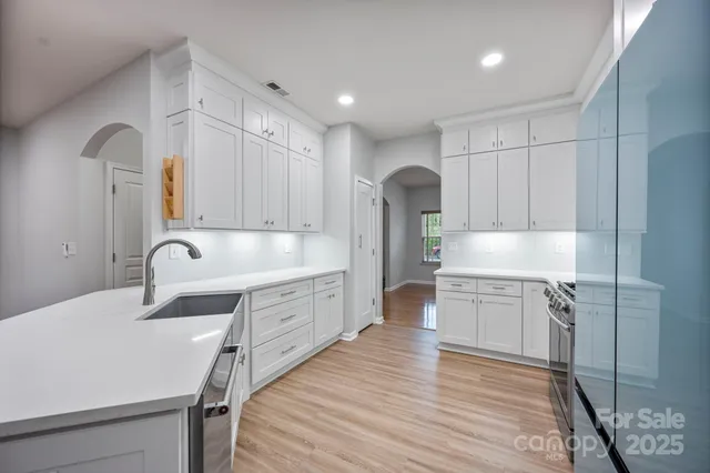 a large white kitchen with kitchen island a sink stainless steel appliances and cabinets