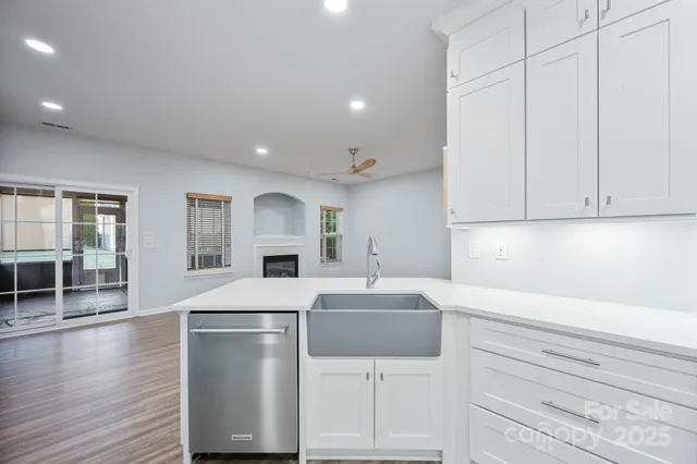 a kitchen with kitchen island a stove a sink and white cabinets with wooden floor