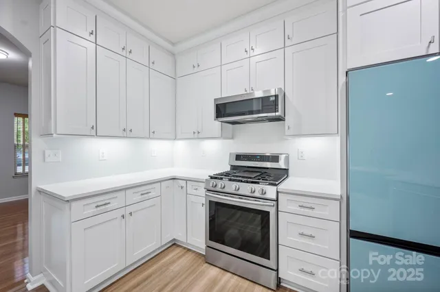 a kitchen with stainless steel appliances white cabinets and a stove top oven
