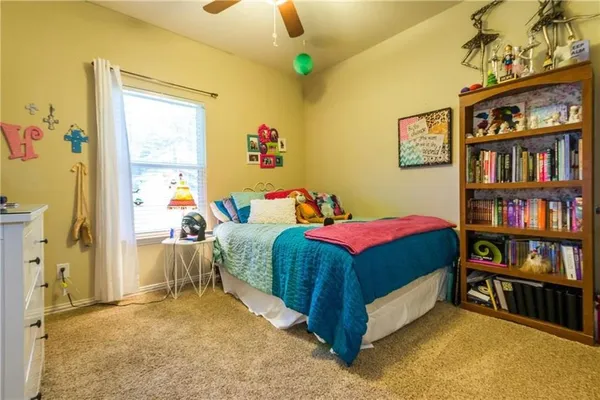 a bedroom with a bed a book shelf and a window