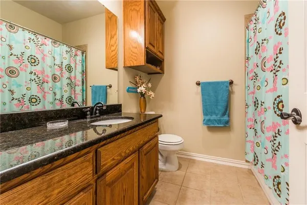 a bathroom with a granite countertop sink and a toilet