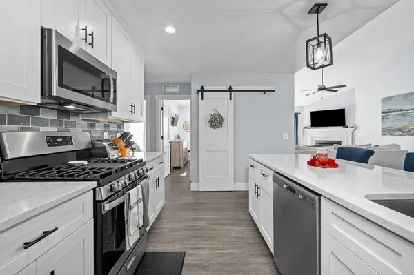 a kitchen with stainless steel appliances granite countertop a stove a sink dishwasher and a microwave with wooden floor