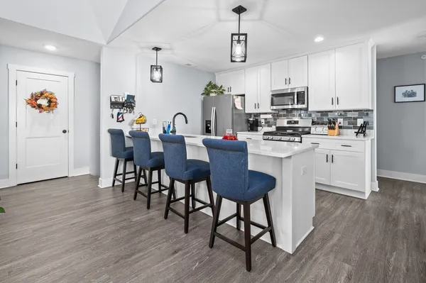 a kitchen with stainless steel appliances a dining table chairs refrigerator and microwave