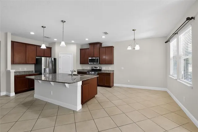 a kitchen with stainless steel appliances granite countertop a stove top oven a sink and a refrigerator