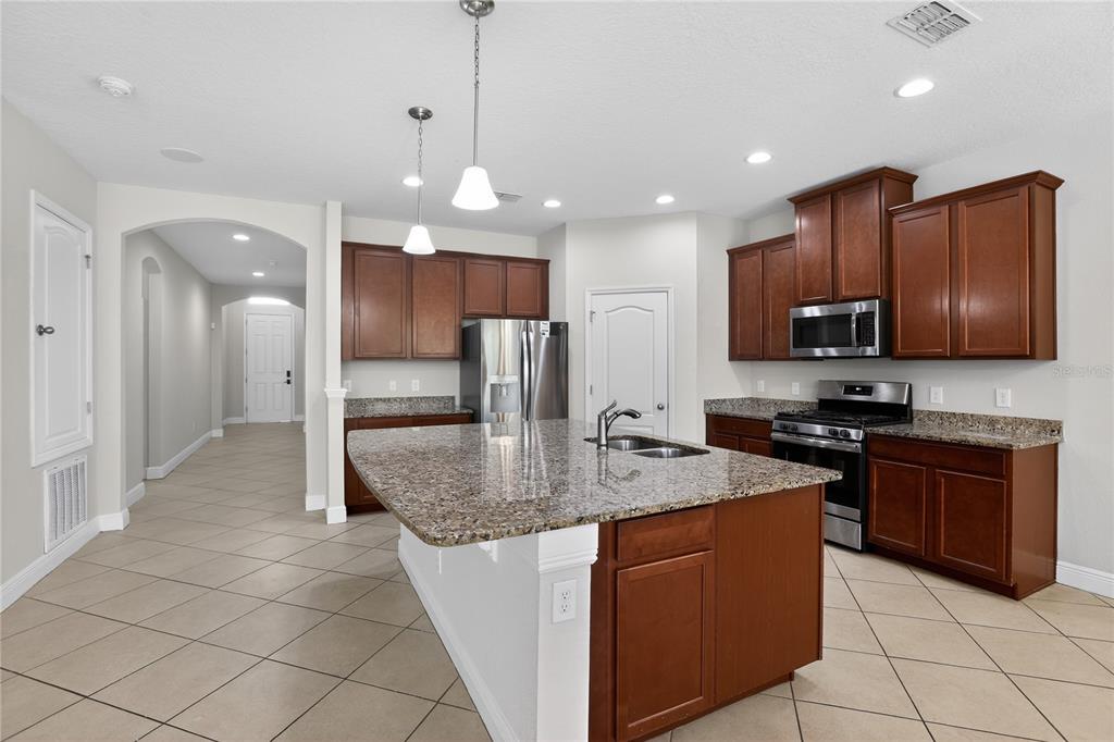 817 Dusty Pine Drive Ocoee, FL 34761 - Photo 7 of 16 a kitchen with stainless steel appliances granite countertop a stove a sink a microwave and a refrigerator