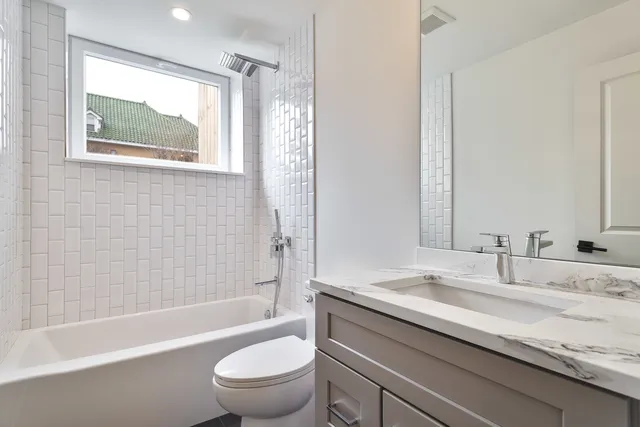 a bathroom with a granite countertop sink a toilet and bathtub
