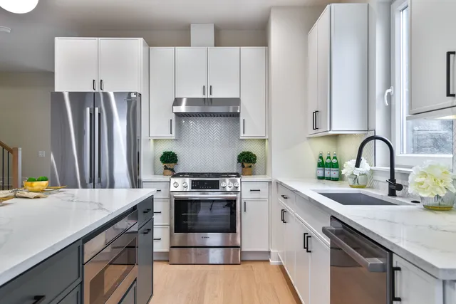 a kitchen with stainless steel appliances a stove a sink and white cabinets