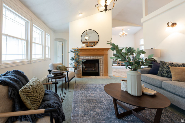 875 East 1300th Street North Mapleton, UT 84664 - Photo 16 of 65 Carpeted living room with a tiled fireplace, arched walkways, vaulted ceiling, and hanging lights