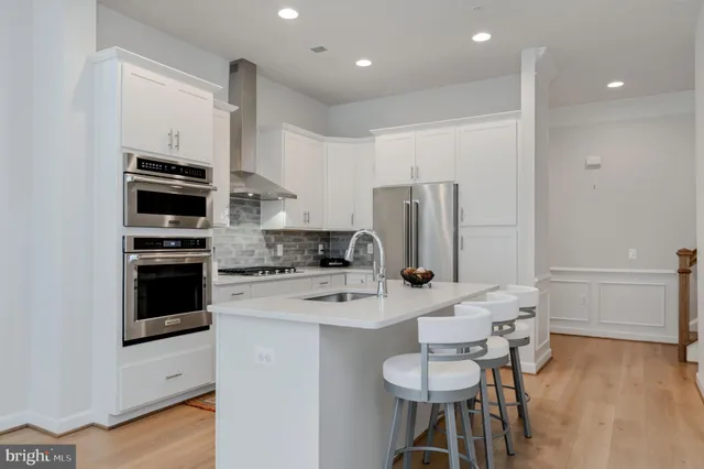 a kitchen with a refrigerator a stove a sink and a dining table with wooden floor