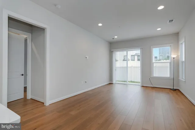 a view of an empty room with wooden floor and windows