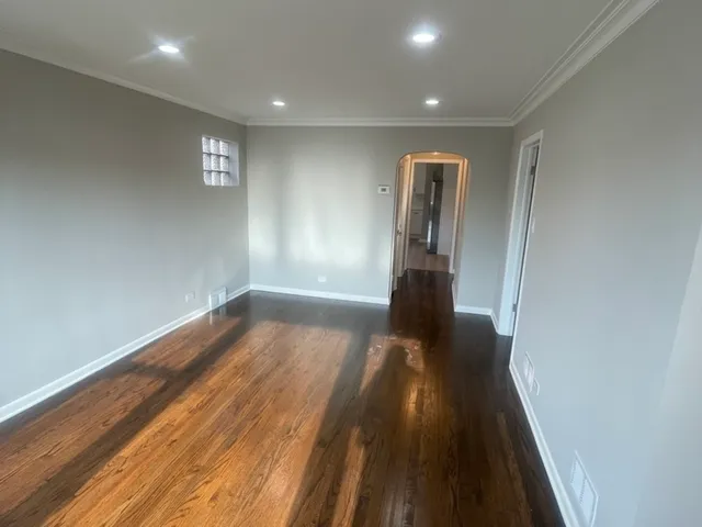 an empty room with wooden floor chandelier fan and windows