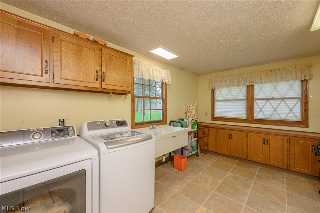 3724 Shellhart Road Barberton, OH 44203 - Photo 22 of 32 Washroom with cabinets, a textured ceiling, washing machine and clothes dryer, sink, and light tile floors