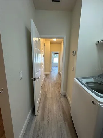 a view of a hallway with wooden floor and a living room