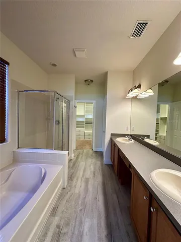 a spacious bathroom with a granite countertop sink a large mirror and a bathtub