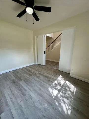 an empty room with wooden floor fan and windows