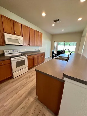 a kitchen with stainless steel appliances a stove a sink a refrigerator white cabinets and wooden floor