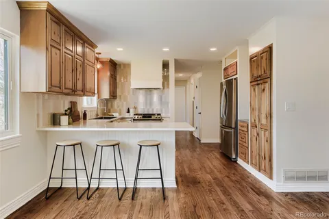 a kitchen with stainless steel appliances granite countertop a refrigerator a stove and white cabinets with wooden floor