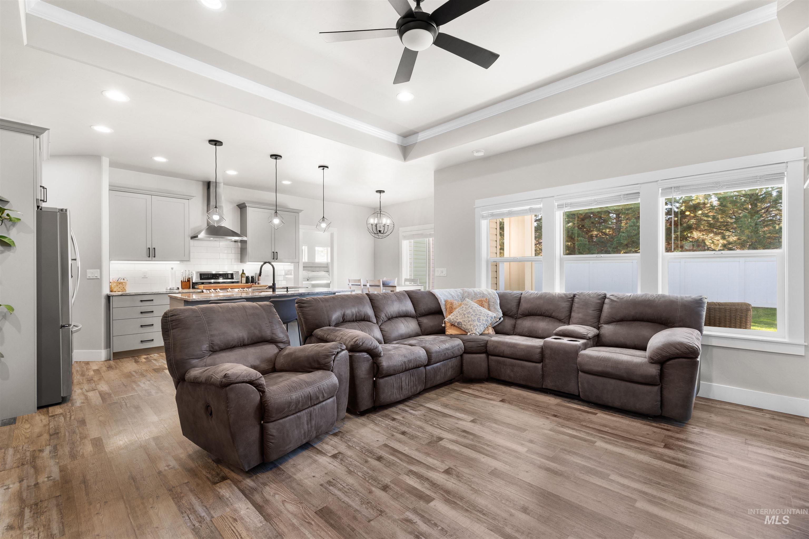 2958 Sunlight Road Twin Falls, ID 83301 - Photo 5 of 40 Open-concept living space featuring wood-finish flooring, a tray ceiling with recessed lighting, and a modern ceiling fan
