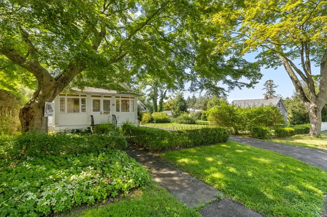 a view of house with a big yard and large trees