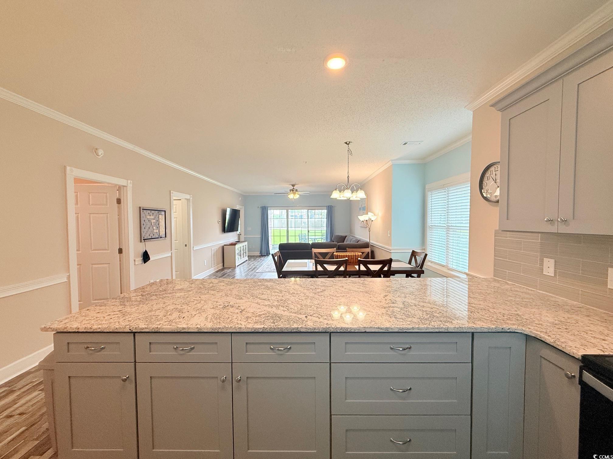 4860 Carnation Circle, Unit 17105 Myrtle Beach, SC 29577 - Photo 29 of 29 Kitchen featuring gray cabinets, light stone countertops, open floor plan, crown molding, and light wood finished floors