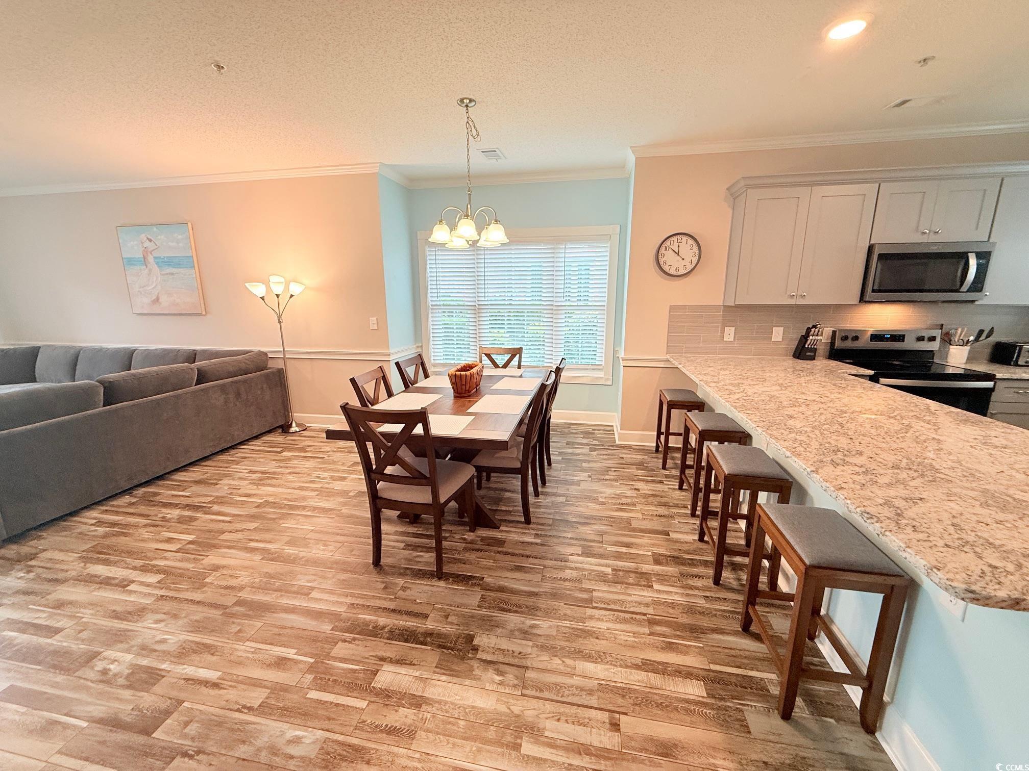 4860 Carnation Circle, Unit 17105 Myrtle Beach, SC 29577 - Photo 6 of 29 Dining area featuring ornamental molding, light wood-style floors, a chandelier, and a textured ceiling