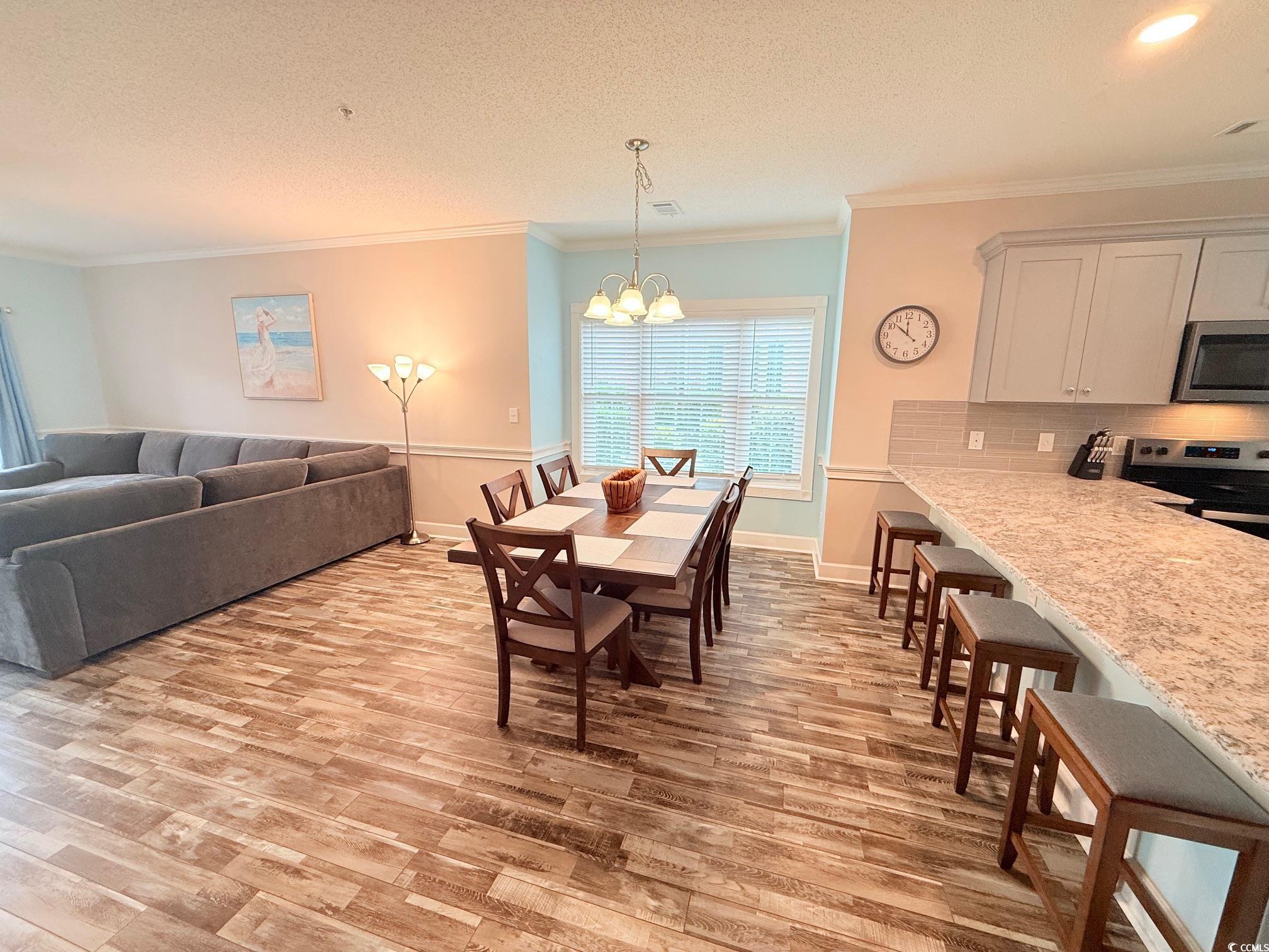 4860 Carnation Circle, Unit 17105 Myrtle Beach, SC 29577 - Photo 7 of 29 Dining room featuring light wood finished floors, ornamental molding, a textured ceiling, and a chandelier