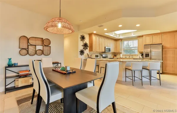 a dining room with stainless steel appliances kitchen island granite countertop a dining table chairs and a microwave
