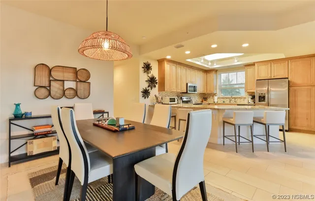 a dining room with stainless steel appliances kitchen island granite countertop a dining table chairs and a microwave