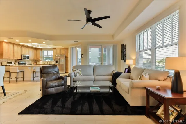 a living room with furniture kitchen view and a large window