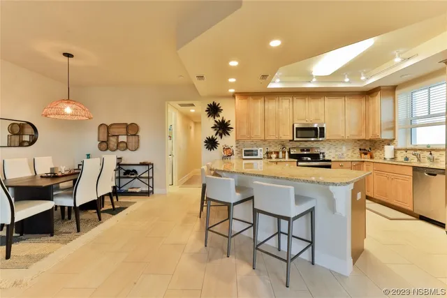 a kitchen with stainless steel appliances kitchen island granite countertop a sink a stove a refrigerator cabinets and chairs