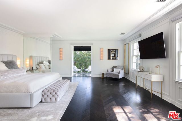 a bedroom with a bed and a flat tv screen on the dresser