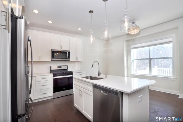 a kitchen with a sink stainless steel appliances a large window and cabinets