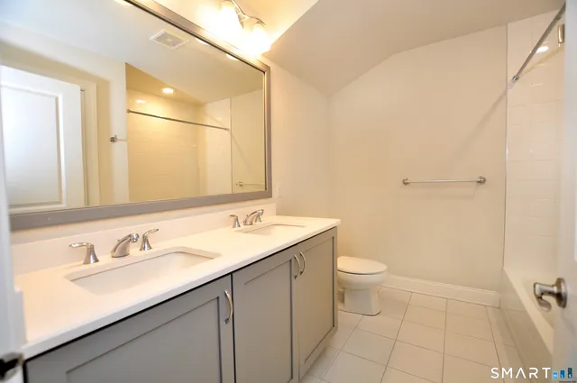 a bathroom with a granite countertop sink a toilet and a mirror