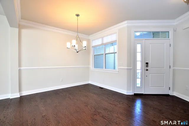 an empty room with wooden floor chandelier and windows