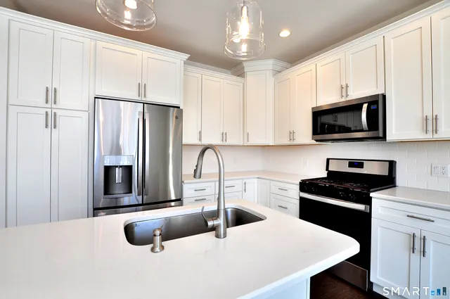 a kitchen with stainless steel appliances a stove a sink a microwave a refrigerator and cabinets