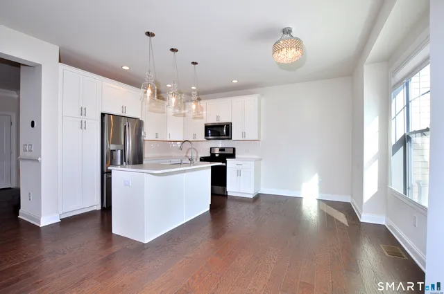 a kitchen with kitchen island granite countertop a refrigerator oven a sink dishwasher and a stove with wooden floor