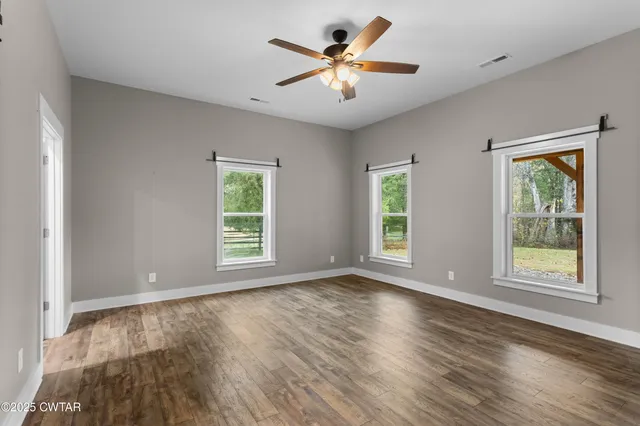 a view of an empty room with a window and wooden floor