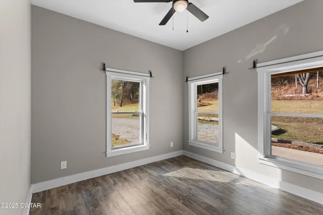 a view of an empty room with a window and wooden floor