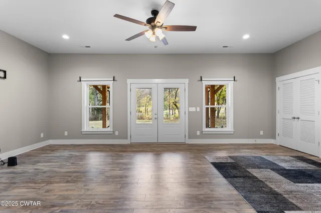 a view of an empty room with a window and wooden floor