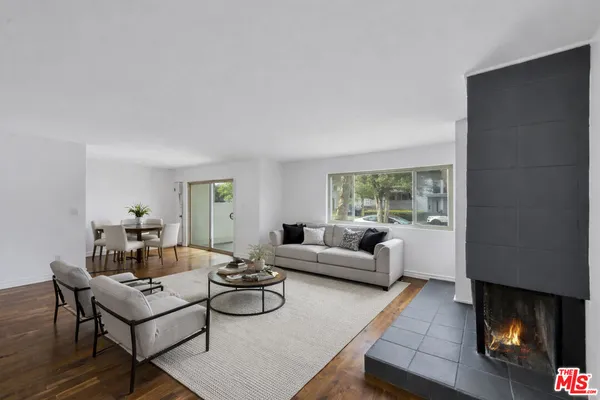 a view of an empty room with wooden floor fireplace and a window